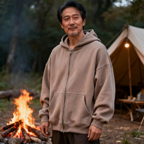 Attributes:
style: Zip-up
fit: Oversized
aspect ratio: 1:1 (Square - Instagram, profile pics)
pocket: Side pockets
color palette: Neutral:Soft Taupe:#B8860B
model sex: Male
model age: Middle aged
model ethnicity: Oriental
background: campfire or campsite